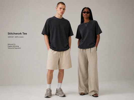 Two fashion models wearing dark gray oversized tees in a studio