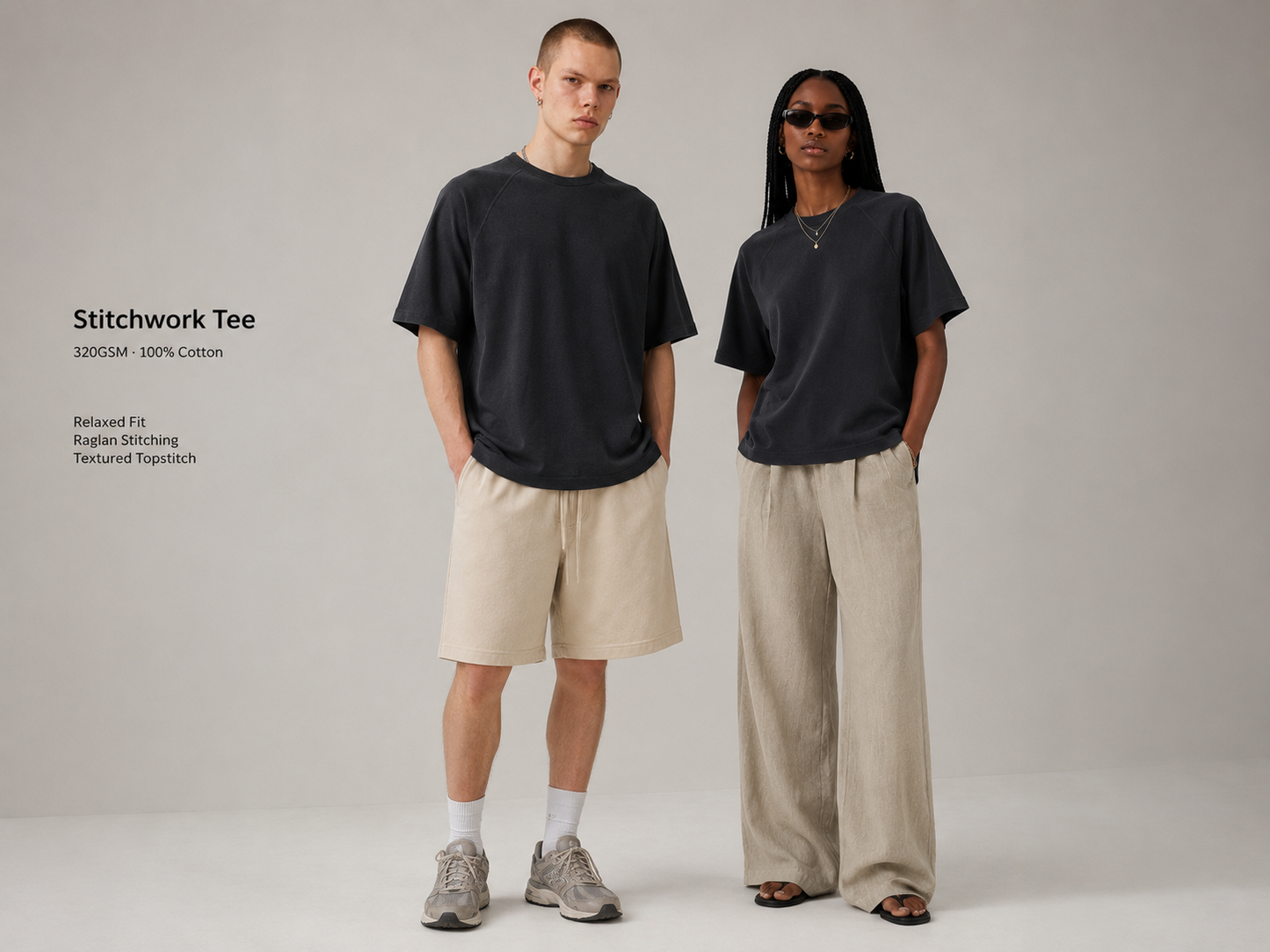 Two fashion models wearing dark gray oversized tees in a studio